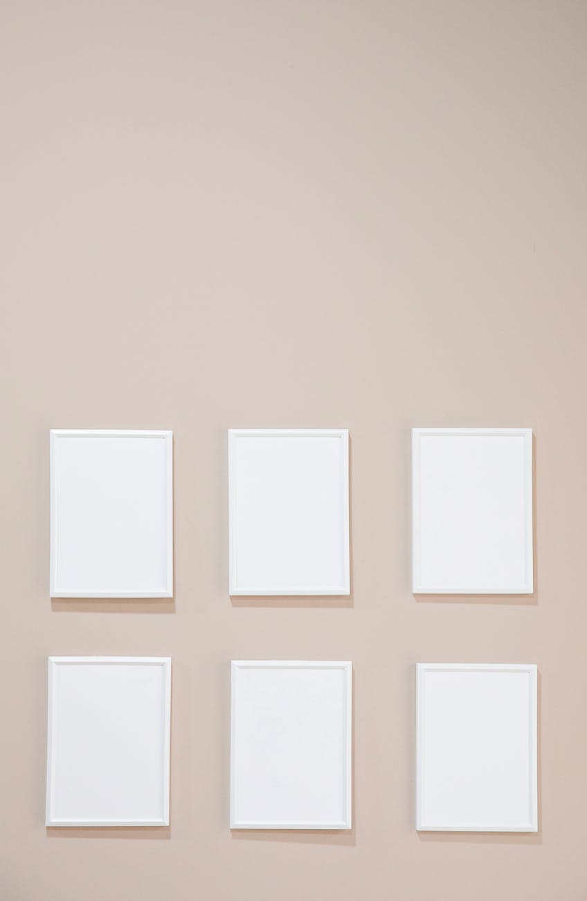 empty white photo frames hanging on gray wall